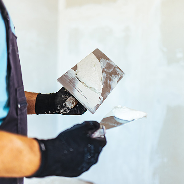 Worker putting plaster on wall using a spatula
